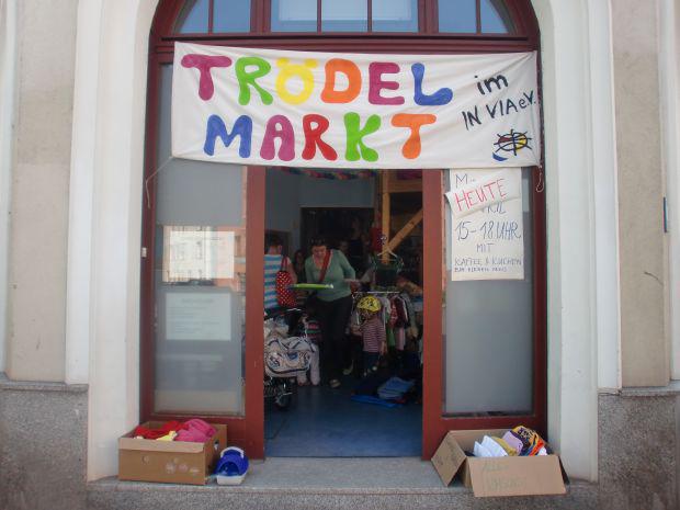 Die Tür der Kita mit einem Schild ‚Trödel Markt im In Via e.V.‘, Kinder sind im Inneren zu sehen.